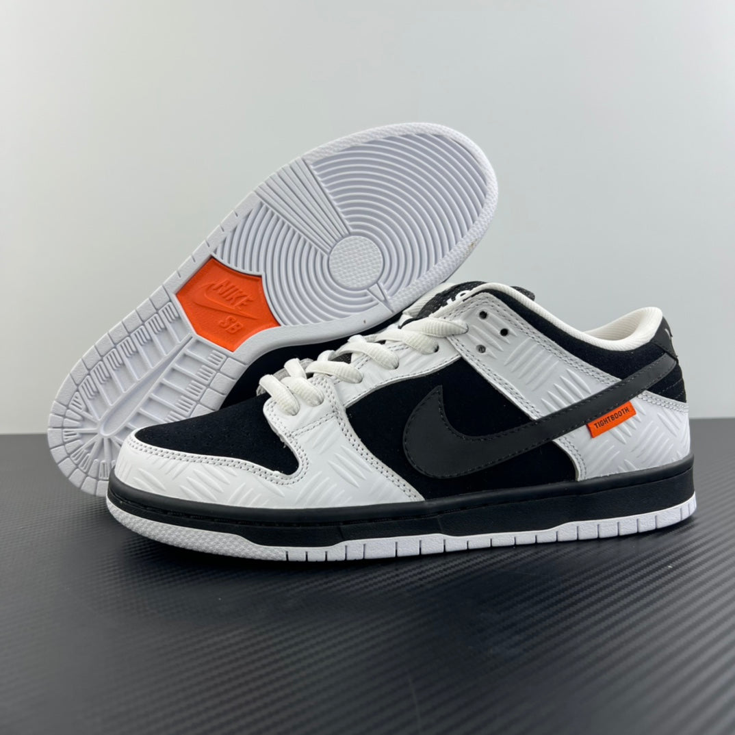 Black and white low-top sneakers with orange accents on the outsole and side panels