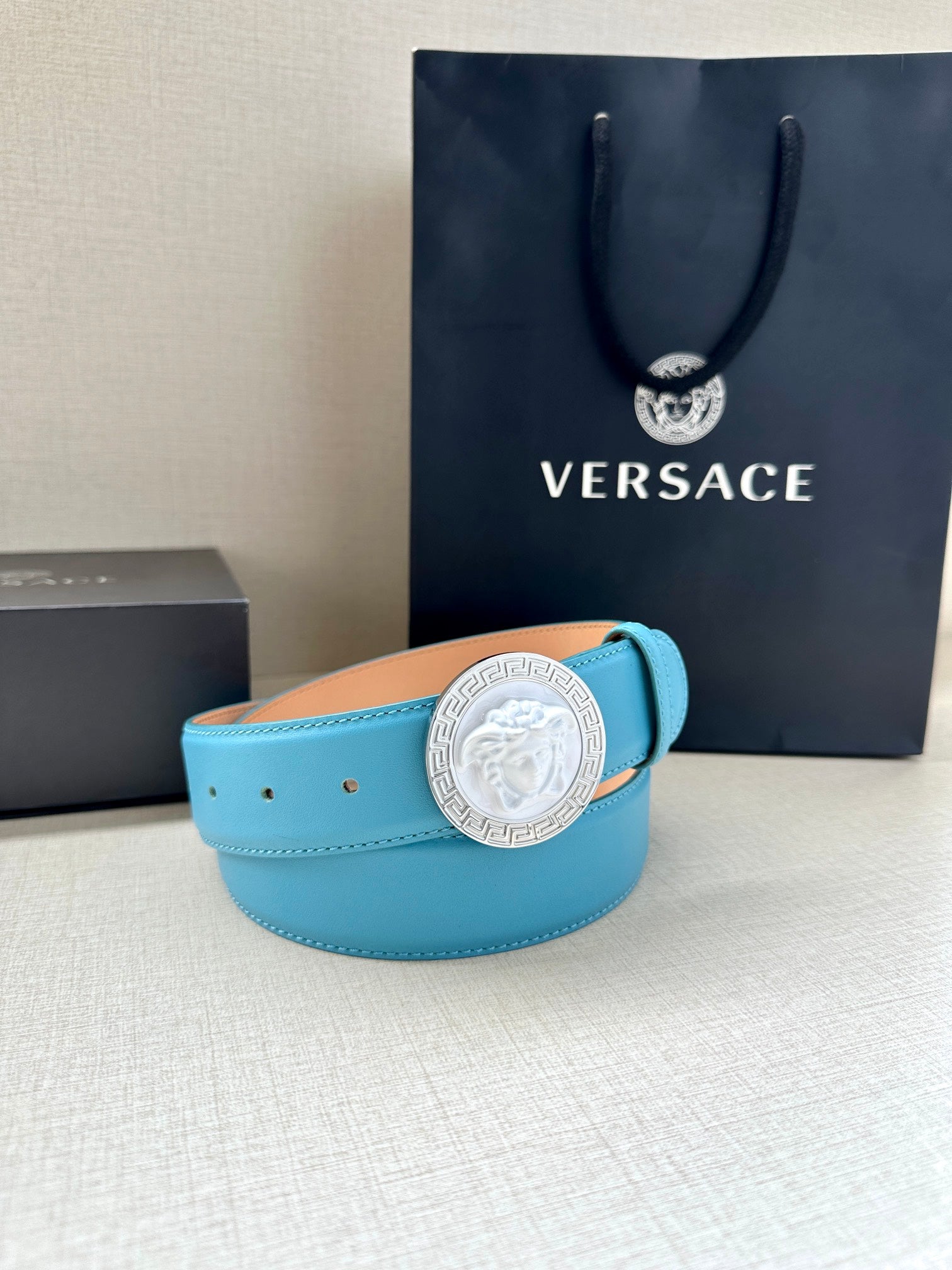 Turquoise leather belt with round silver medallion buckle and curved strap on display