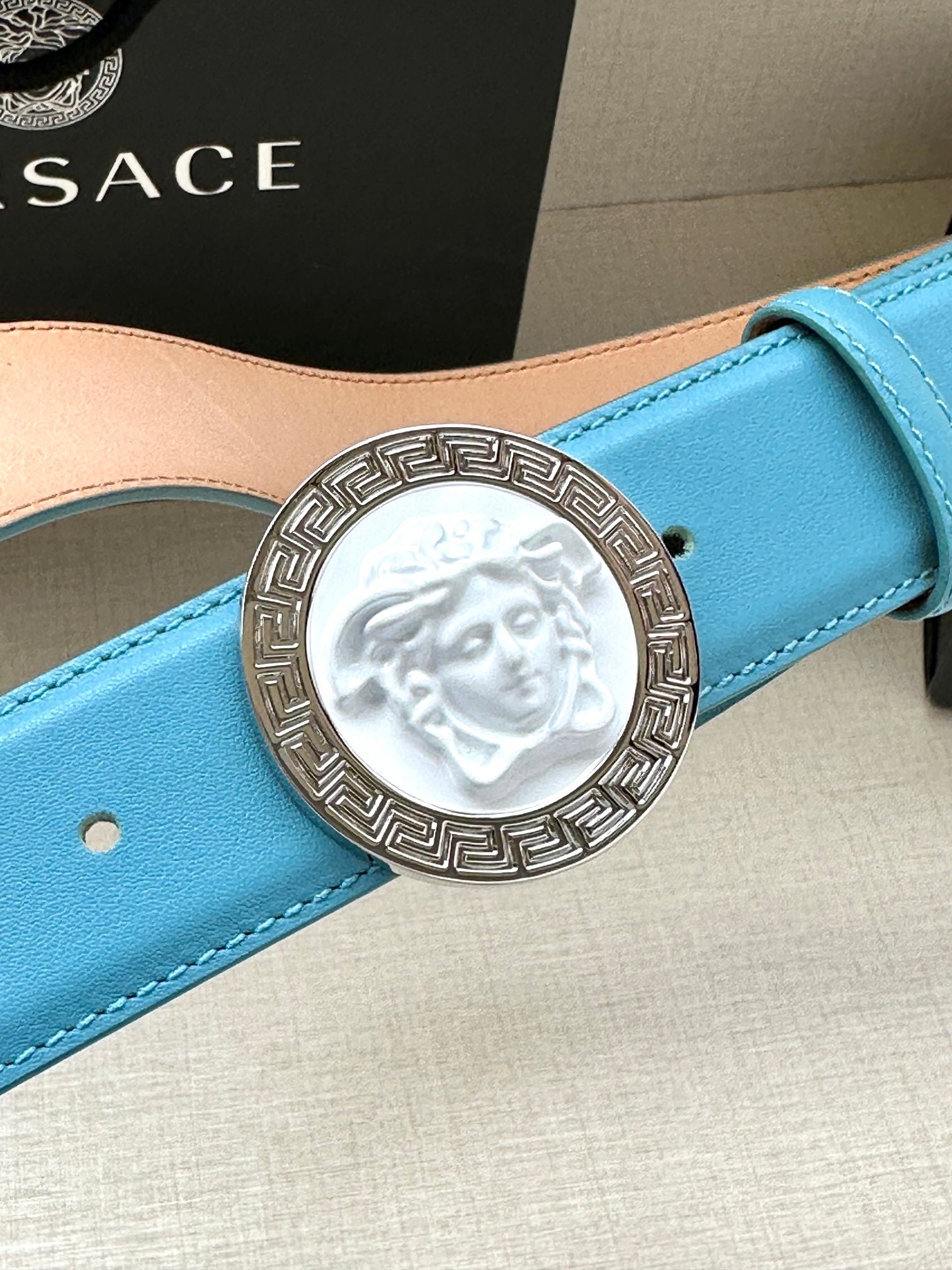 Turquoise leather belt with round silver medallion buckle featuring Medusa relief