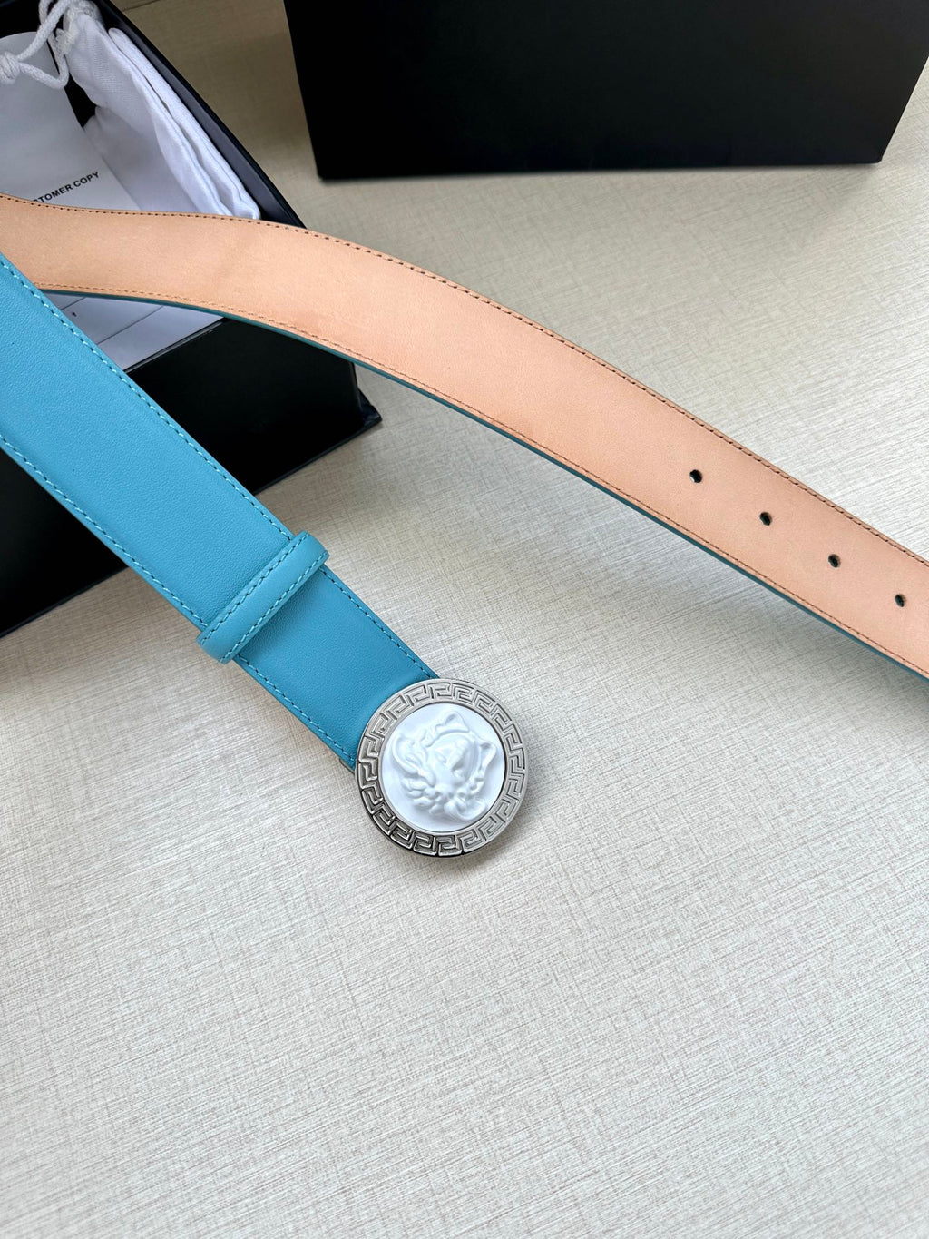 Turquoise leather belt strap with silver medallion buckle and row of perforation holes