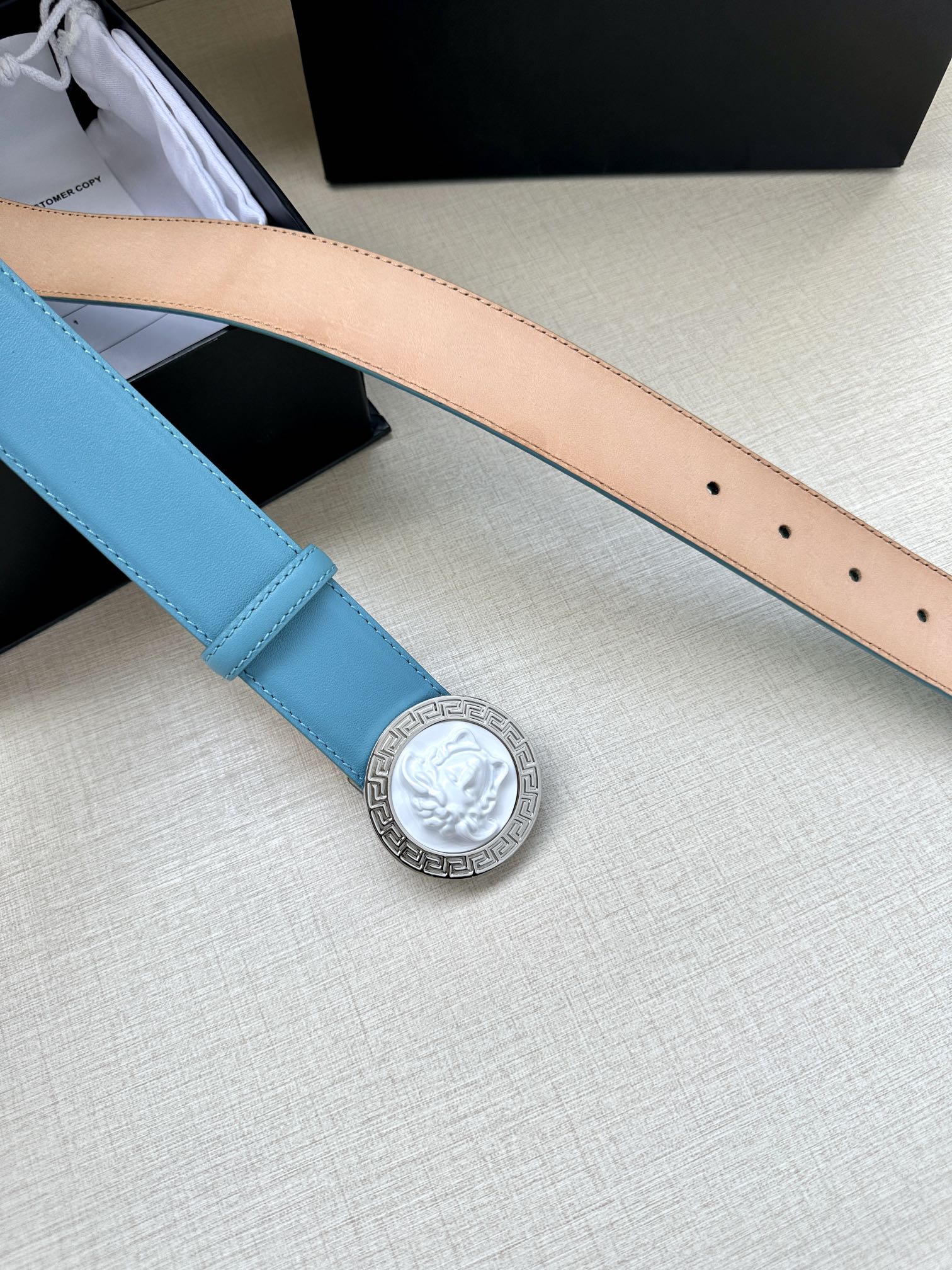 Turquoise leather belt strap with silver medallion buckle and row of perforation holes