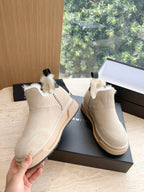 Amiri ankle boots in light beige suede with faux fur trim, shown with hand holding