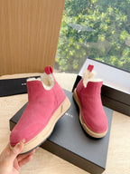 Pink suede Chelsea boot held in hand; faux shearling collar and beige sole