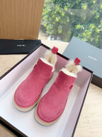 Pink suede Chelsea boots with faux shearling trim and red pull tabs