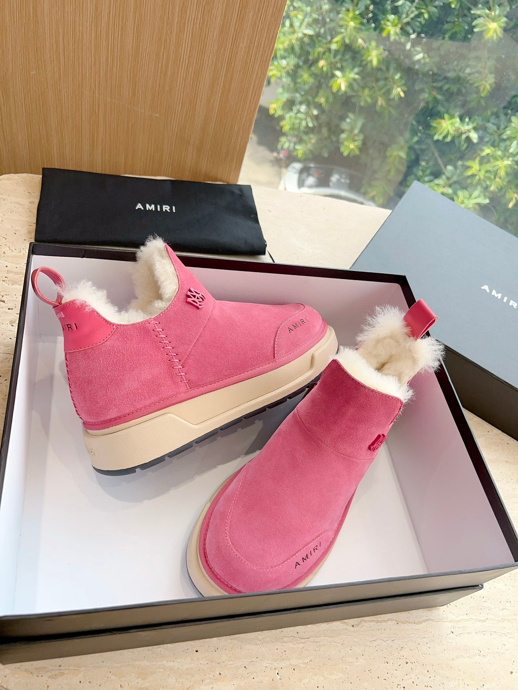 Pair of pink suede Chelsea boots with faux shearling lining and red tabs