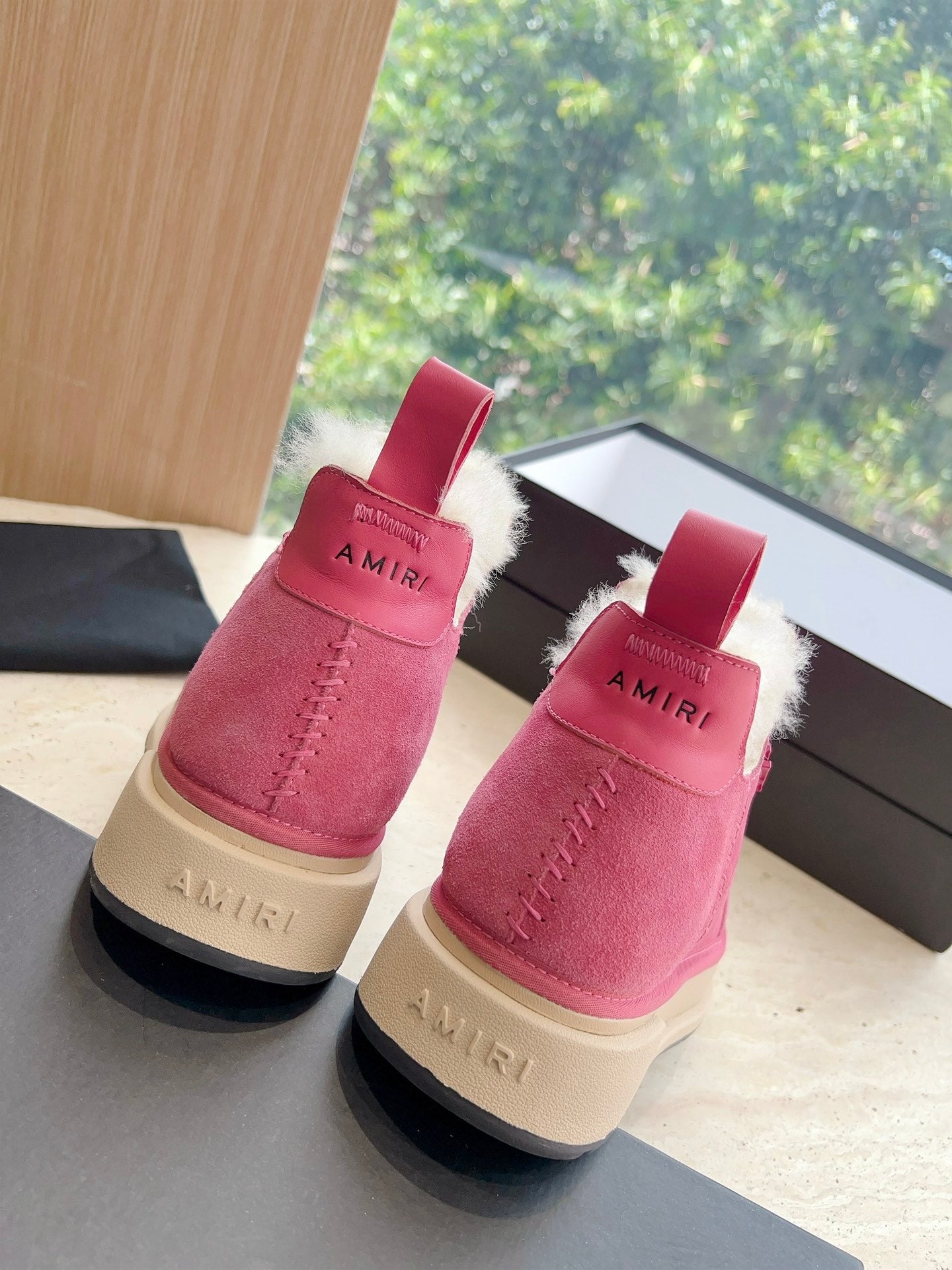Two pink suede Chelsea boots with faux shearling trim and red pull loops