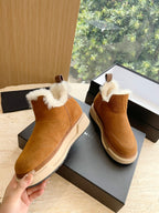 Amiri tan suede ankle boots with white shearling trim, held near the box