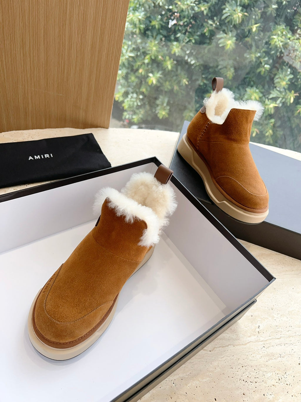 Amiri tan suede ankle boots with white shearling cuffs, shown on their side