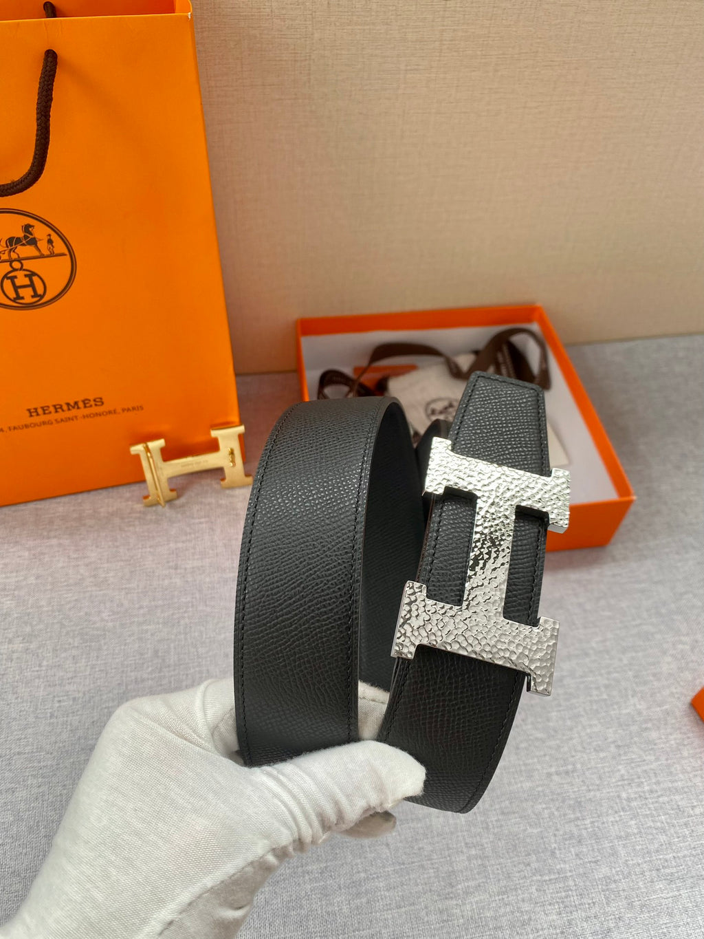 Hermes belt in hand: black strap with large metallic H buckle