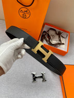 Black leather belt with gold H buckle on textured strap, shown laid flat