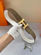 White-and-brown leather belt with gold-tone H buckle; outer strap shown curved.