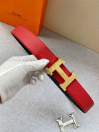Red leather belt with gold-tone H buckle and red strap, held on a hand