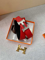 Red leather belt with silver-and-gold H buckle pieces on a display tray