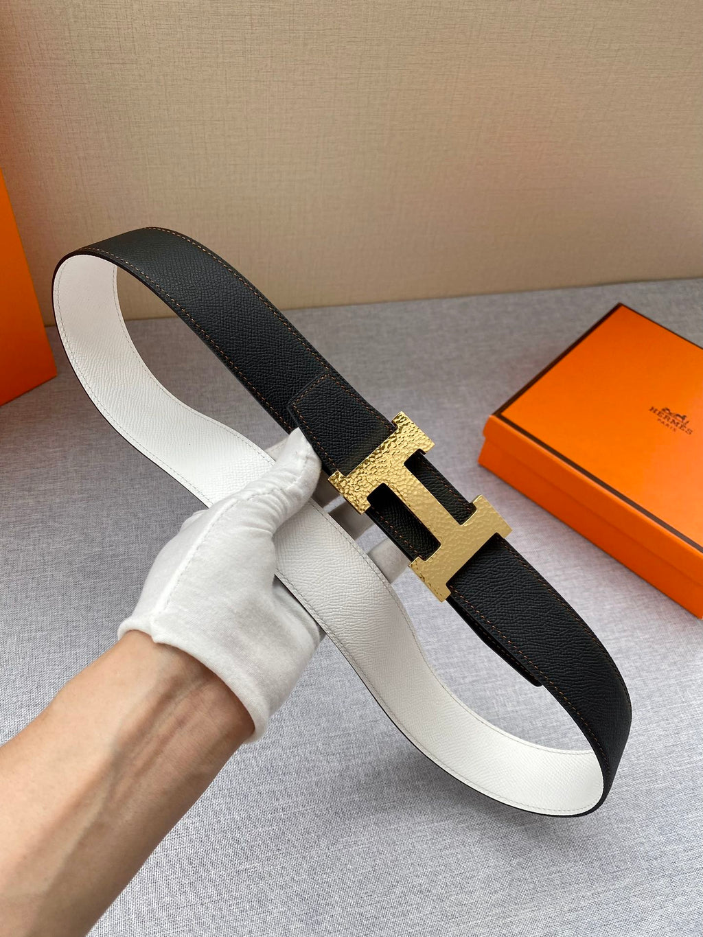 Black leather belt with gold-tone H buckle, shown from side angle