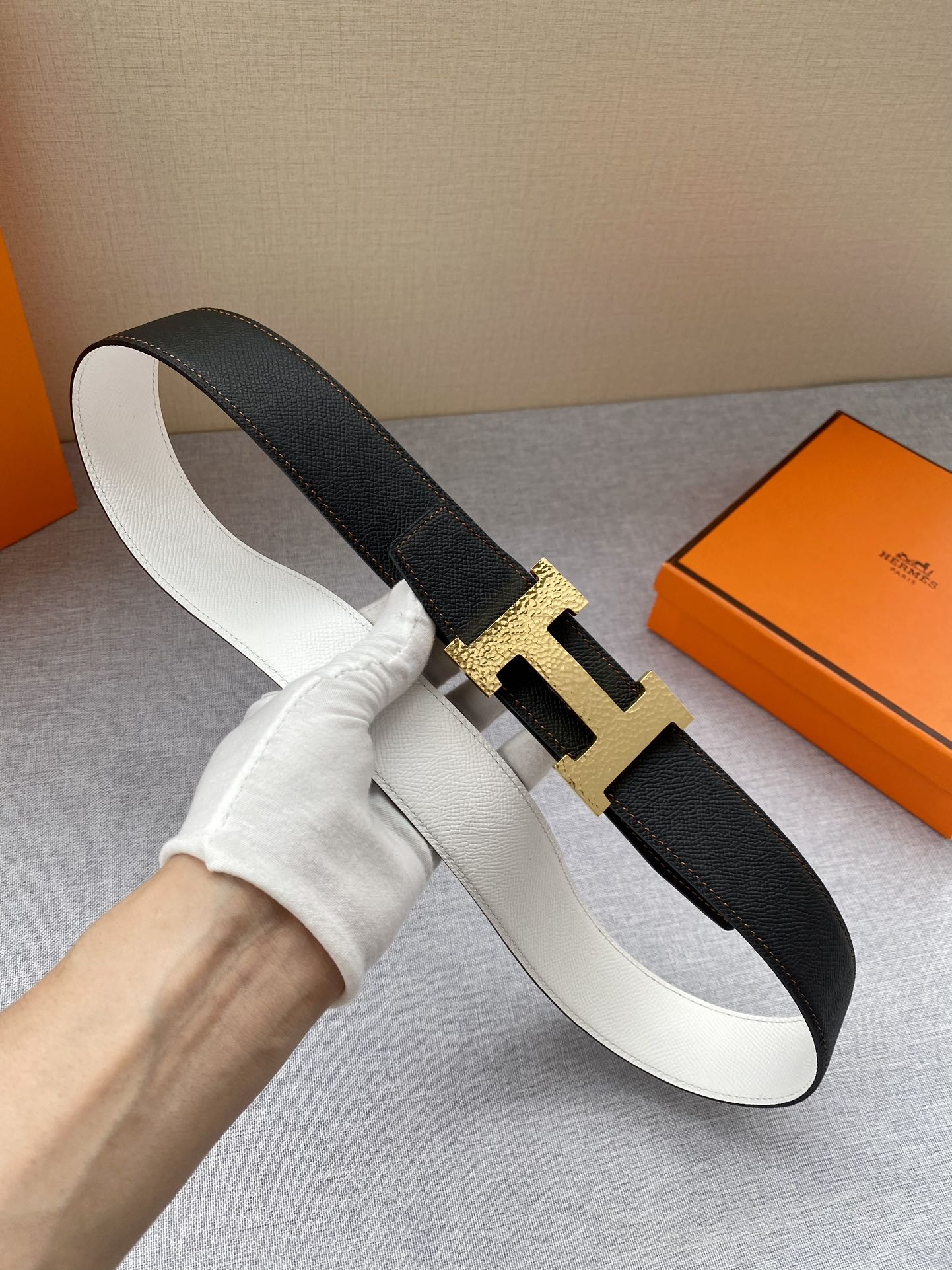 Black leather belt with gold-tone H buckle, shown from side angle