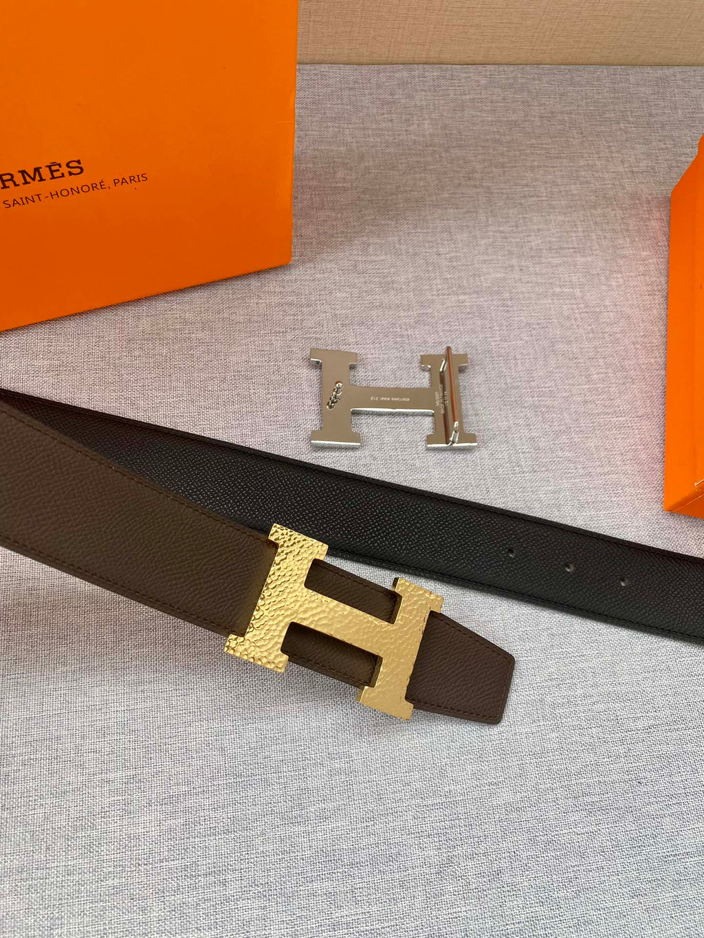 Hermes belt with dark strap and gold H buckle, detail view