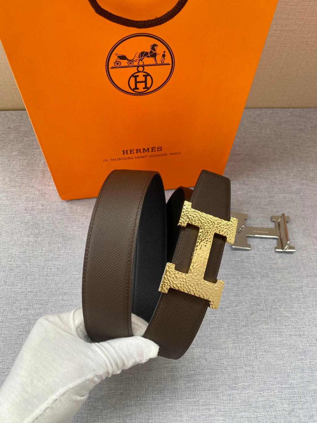 Hermes leather belt with dark strap and gold H buckle, side view