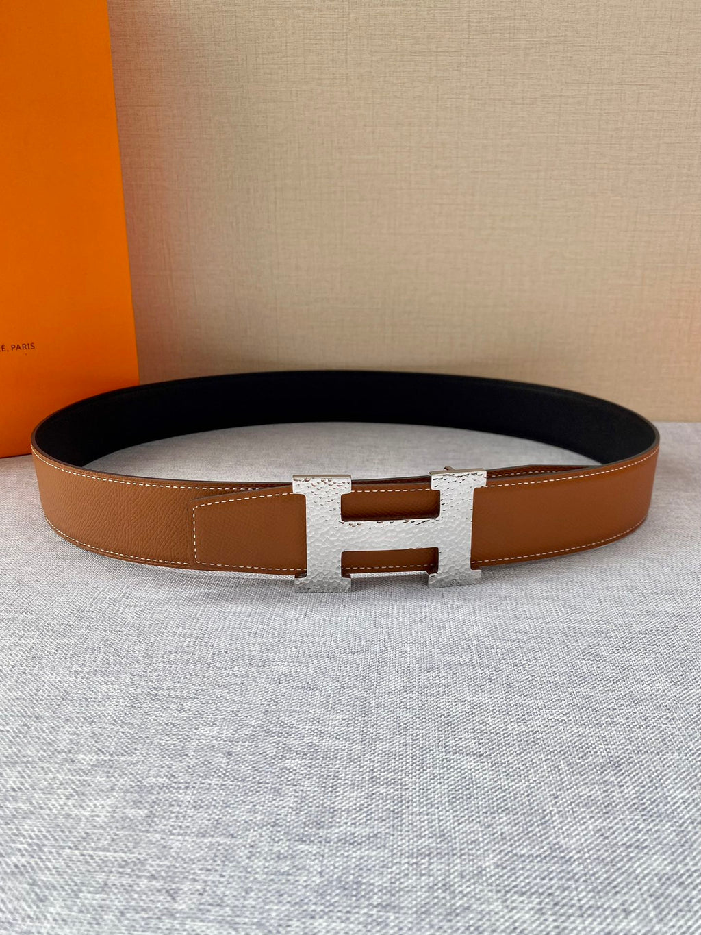 Tan leather belt with gold-tone square buckle; flat lay with smooth strap edges.