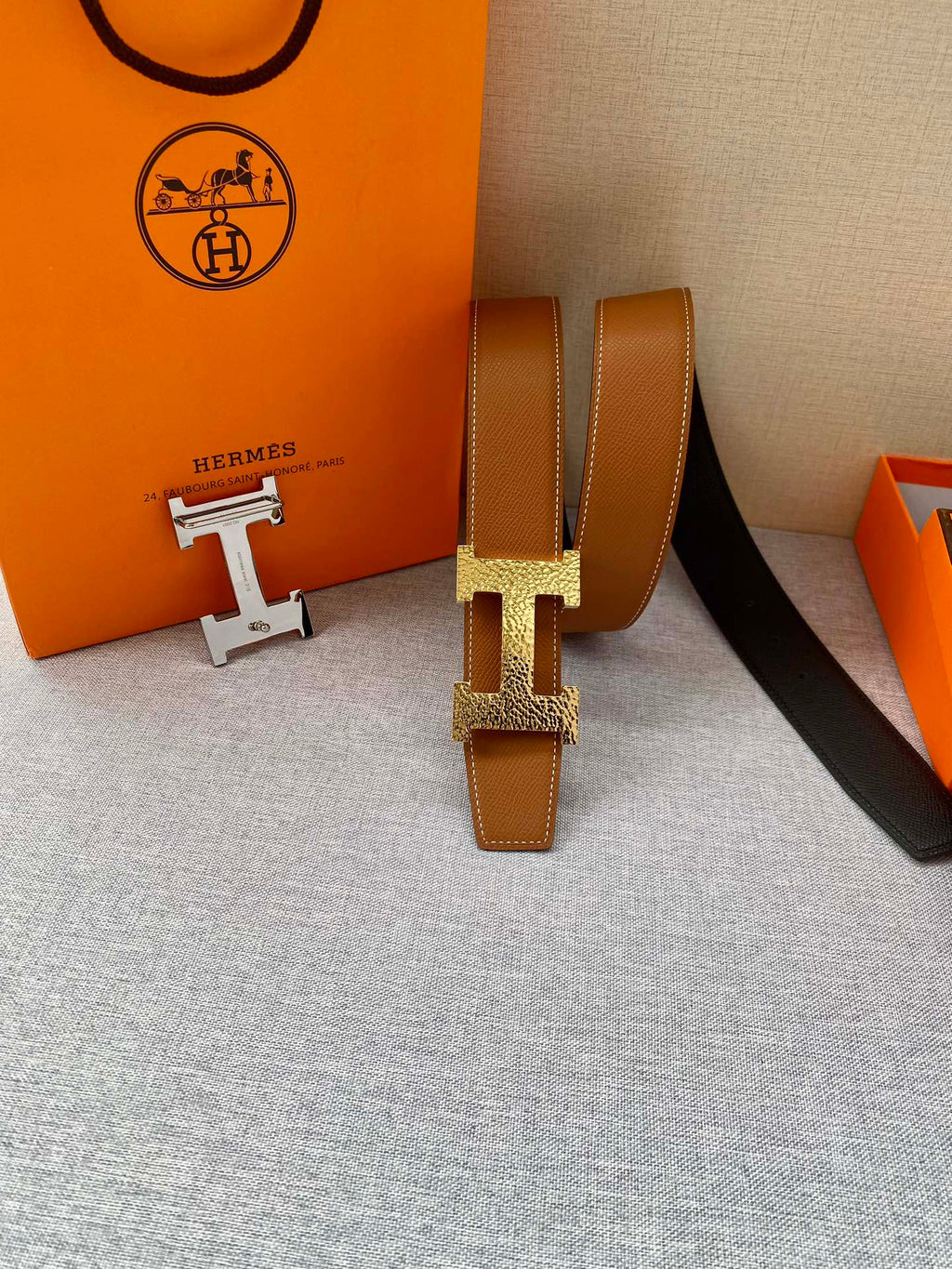 Tan leather belt with gold-tone H buckle and keeper; belt end and hardware shown.