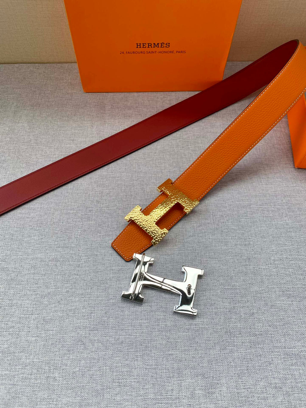Orange leather belt with gold H buckle and burgundy underside
