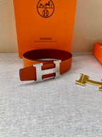 Orange leather belt with silver-toned H buckle and punched holes