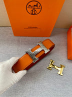 Orange leather belt with gold H buckle and rhinestone-style detailing