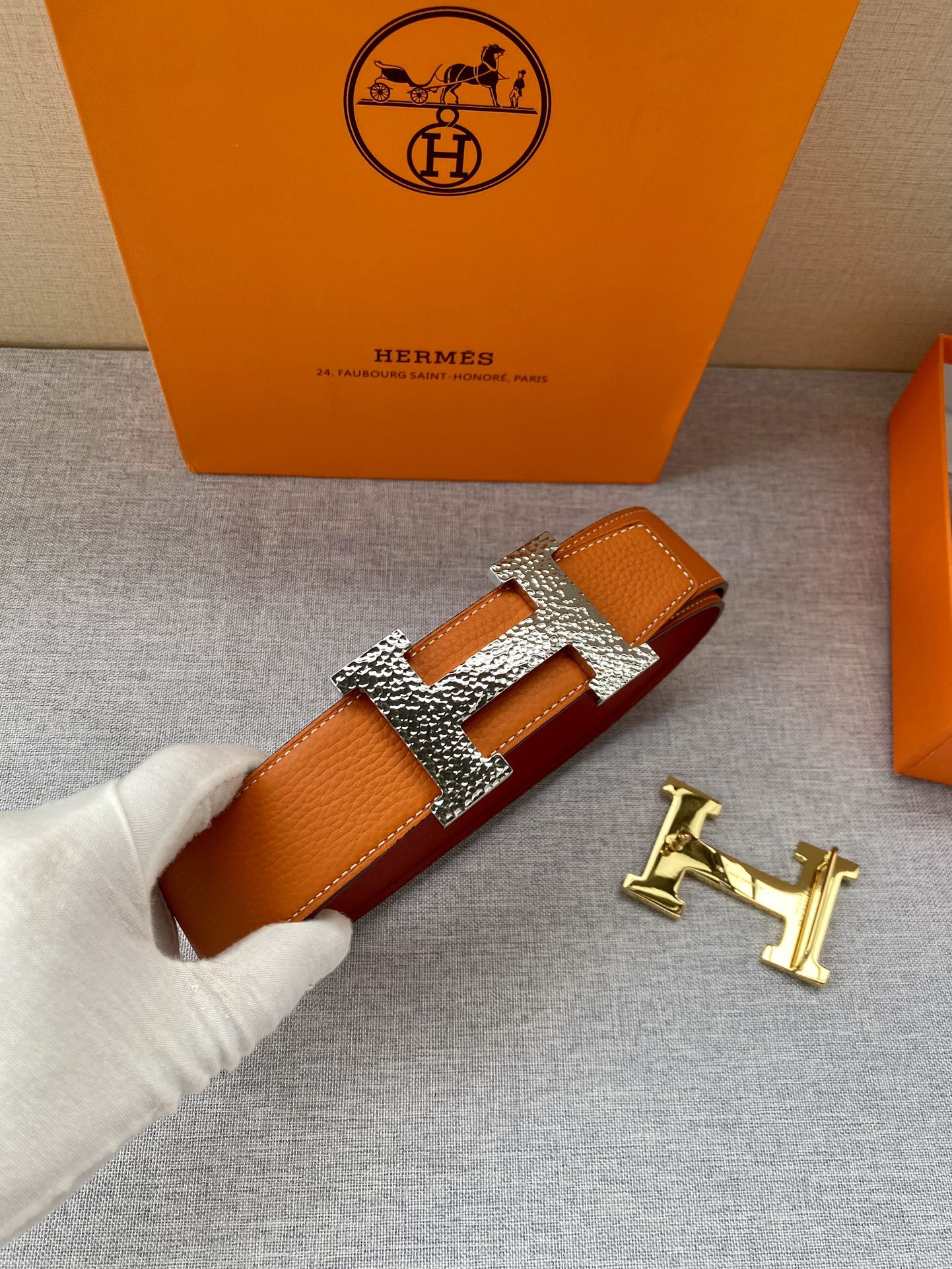 Orange leather belt with gold H buckle and rhinestone-style detailing