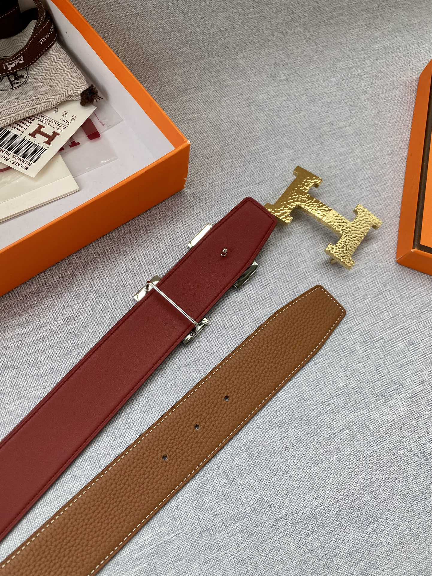 Leather belt with gold H buckle, showing red strap and brown strap