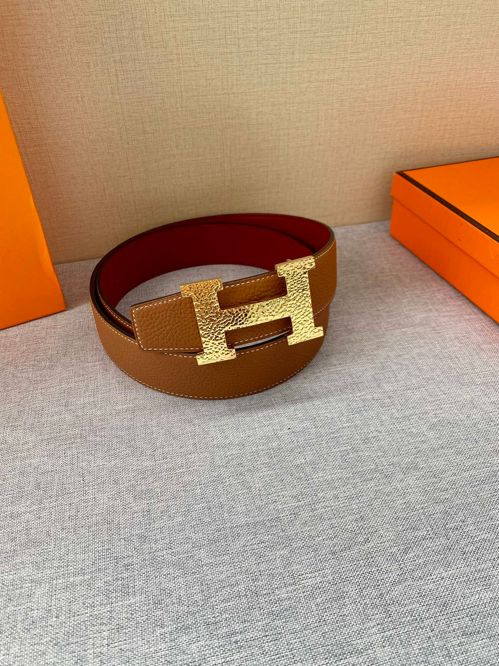 Hermes leather belt with tan/brown strap and gold H buckle over burgundy band