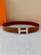 Brown leather belt with gold H buckle and red underside visible