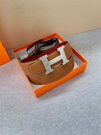 Brown leather belt with gold H buckle, laid flat