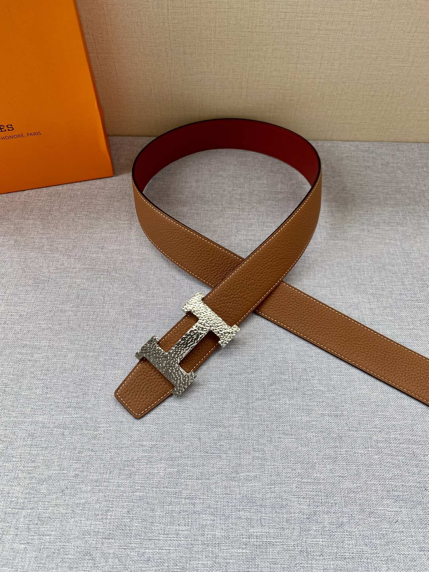 Brown leather belt with gold buckle and maroon underside