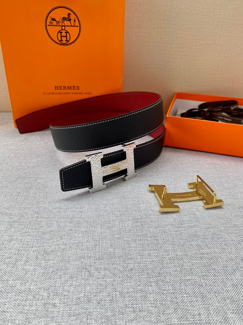 Hermes belt laid flat: black textured strap with gold-tone buckle and small matching leather pouch.