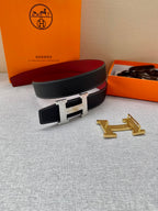 Hermes belt laid flat: black textured strap with gold-tone buckle and small matching leather pouch.