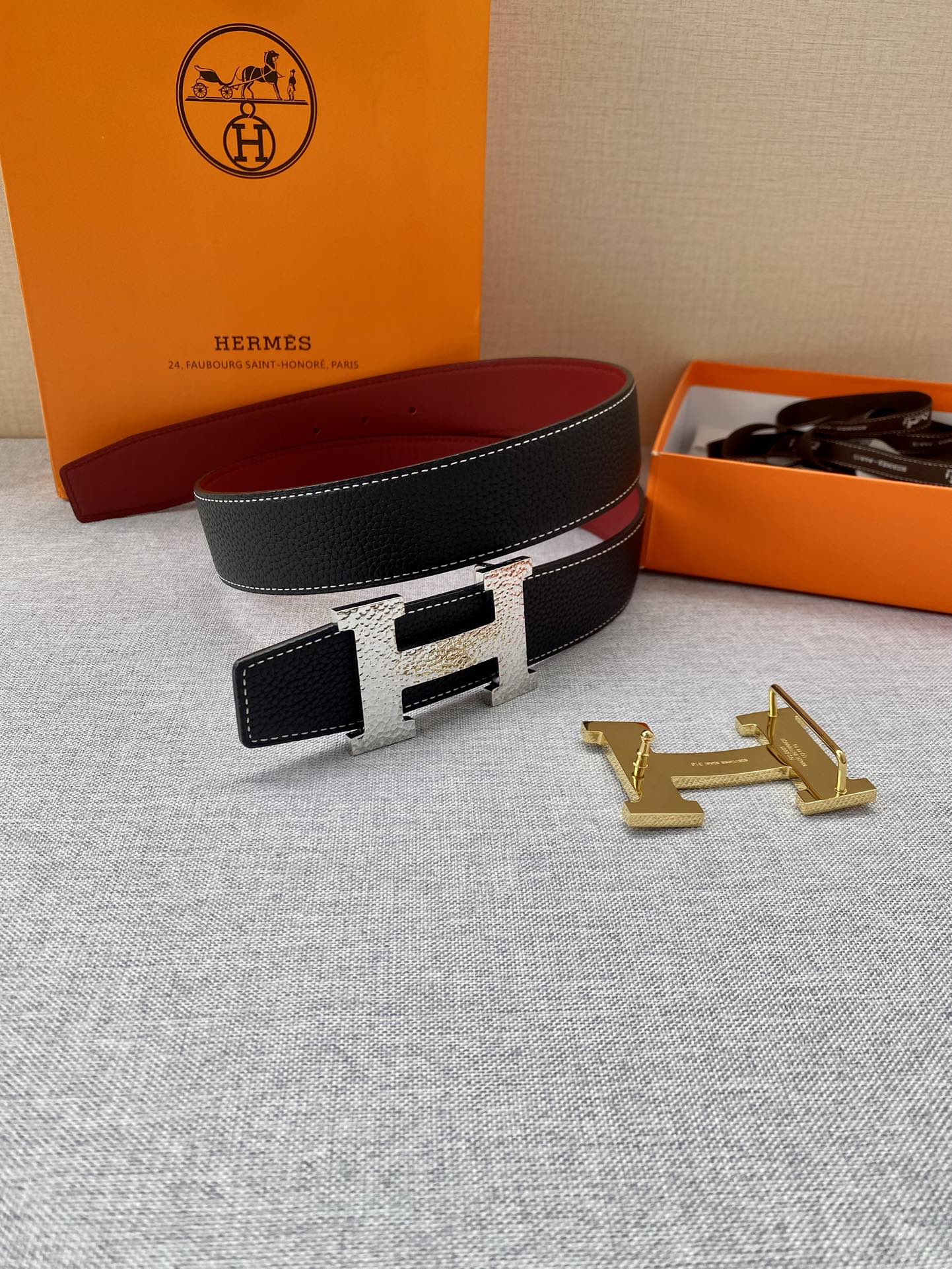 Hermes belt laid flat: black textured strap with gold-tone buckle and small matching leather pouch.