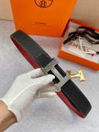 Hermes belt in black textured leather with silver-tone H buckle, red underside and strap end.