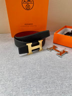 Hermes belt on display: black textured leather, gold-tone H buckle, red lining, with accessories.