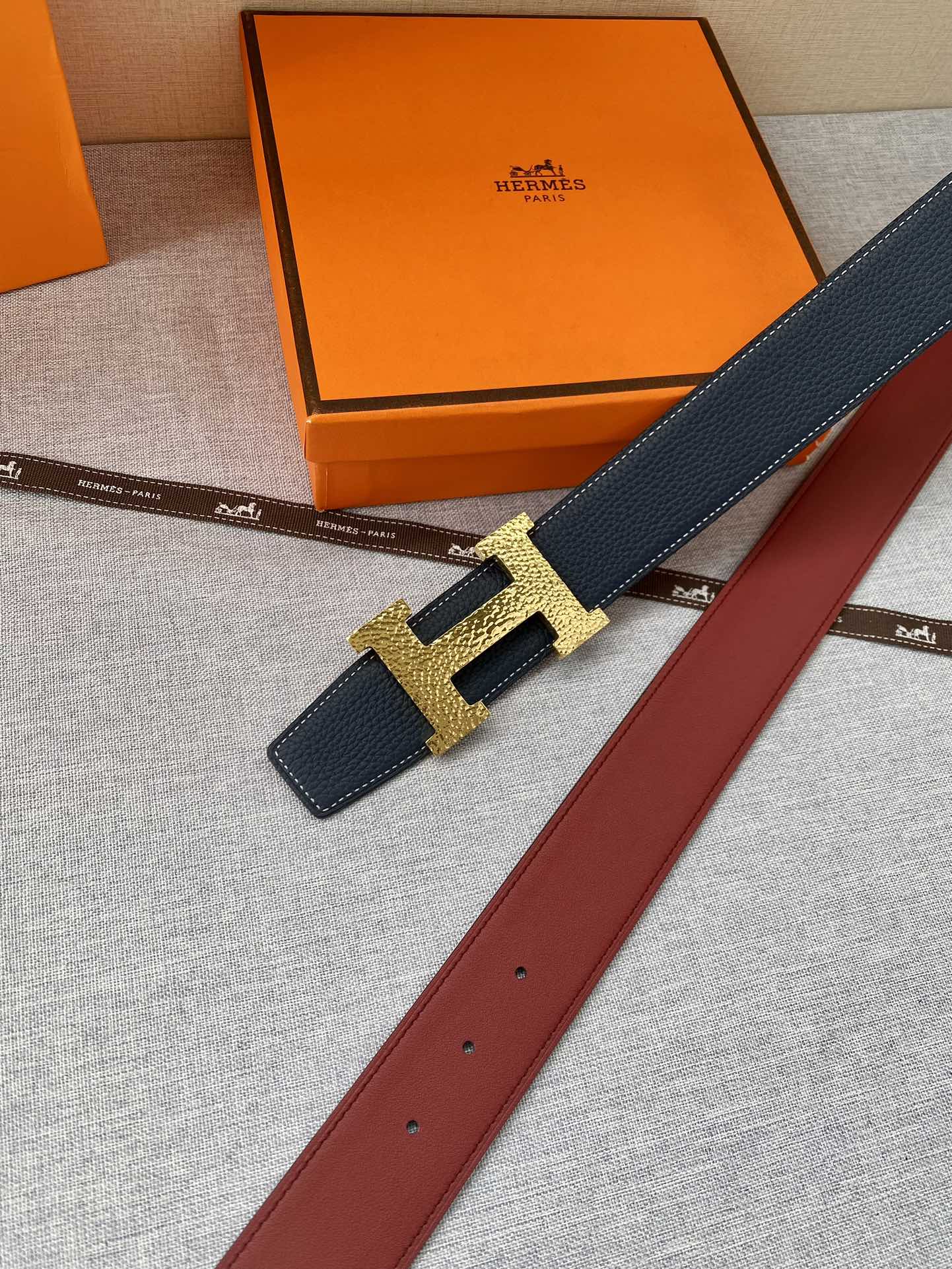 Navy leather belt with gold-tone H buckle and punched strap holes