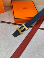 Hermes dark blue leather belt with gold H buckle and red underside strap.