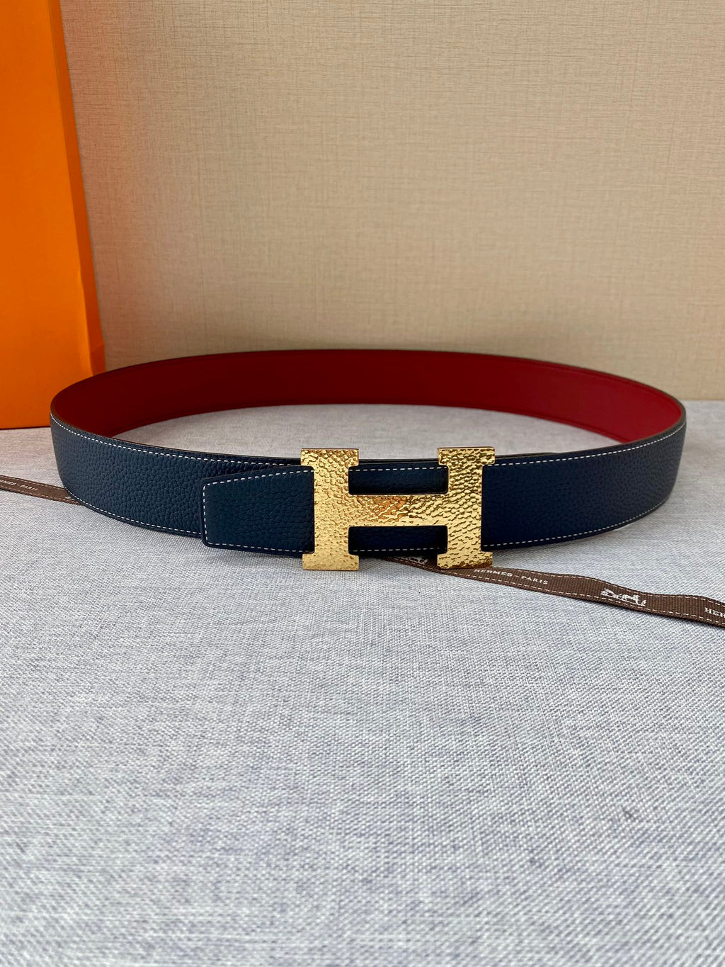 Navy leather belt with gold-tone H buckle and red inner lining