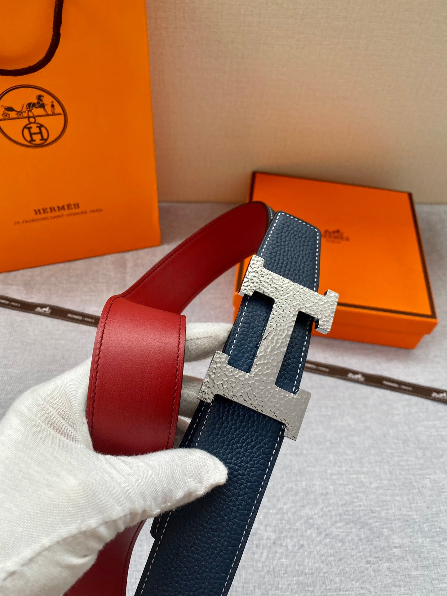 Navy leather belt with gold-tone H buckle over red lining