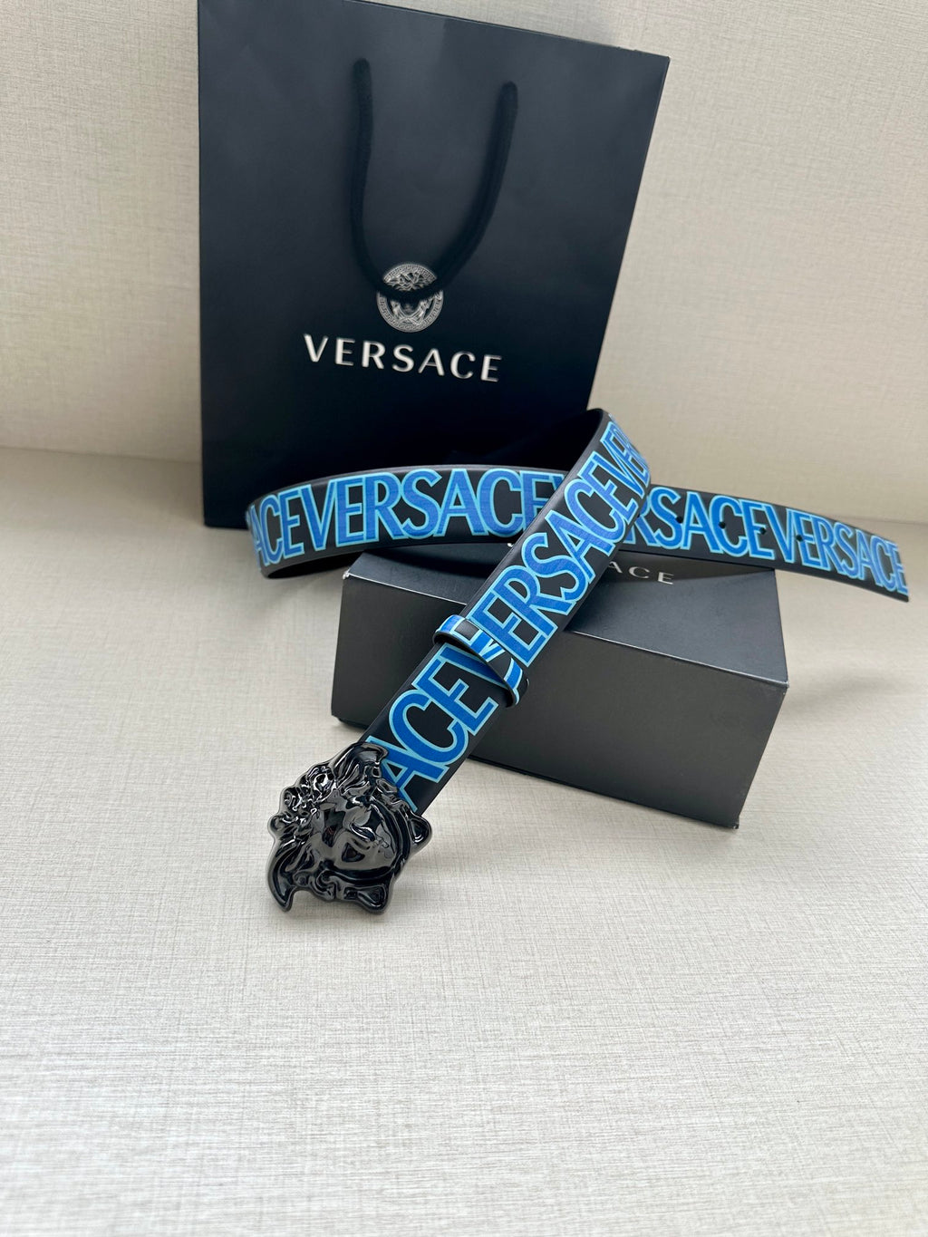 Designer belt with blue logo strap and ornate silver lion buckle, with gift box