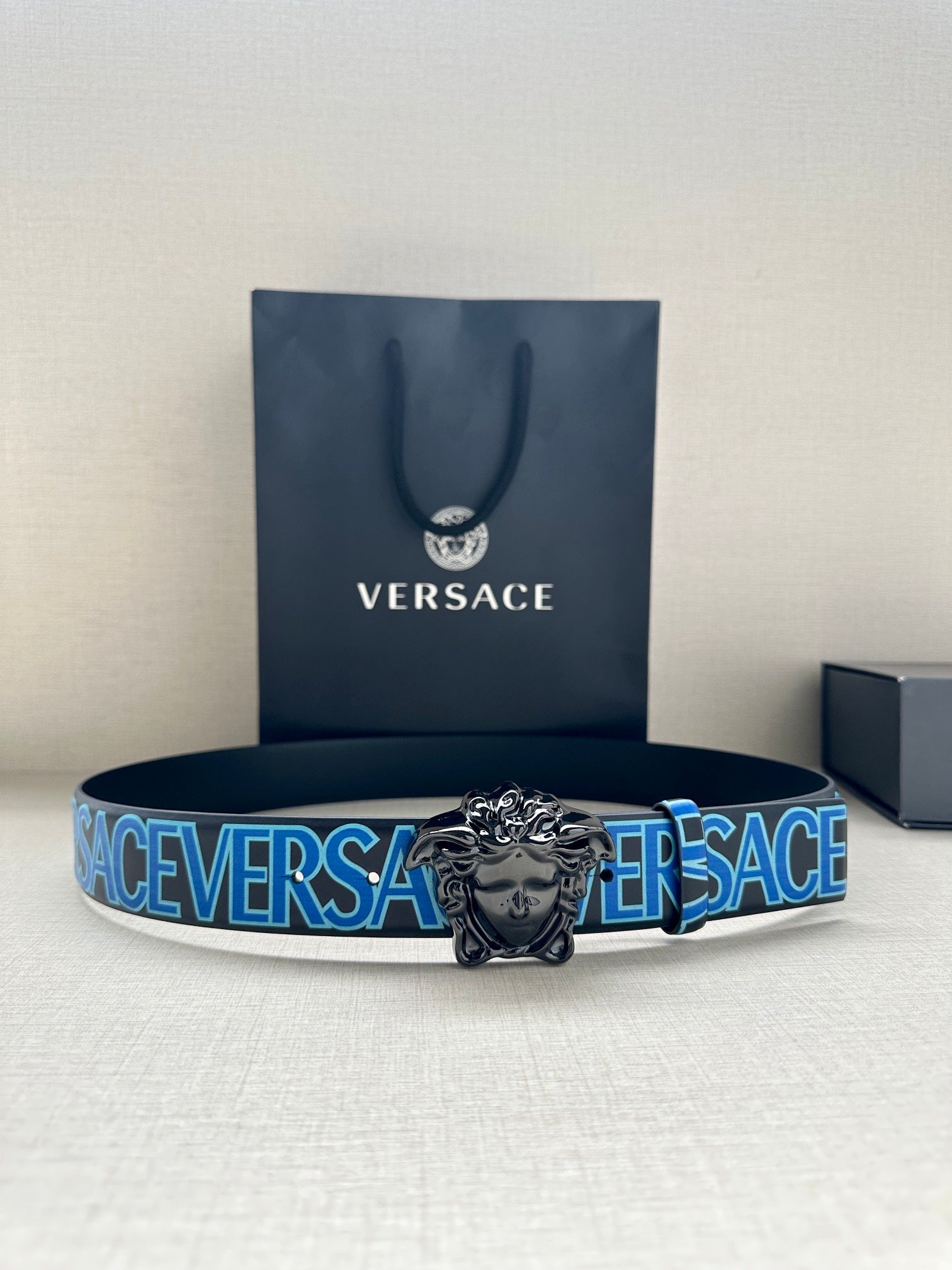 Versace belt with blue logo strap and ornate silver lion buckle, on display with box