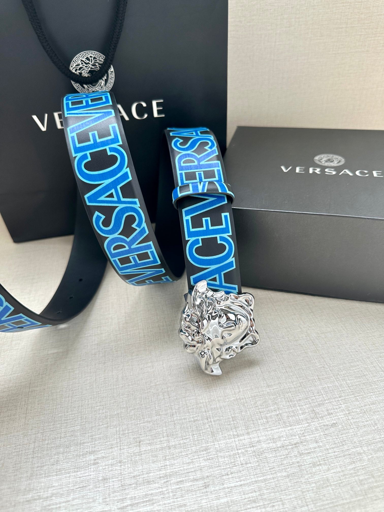 Versace belt close-up: blue logo webbing and silver Medusa buckle