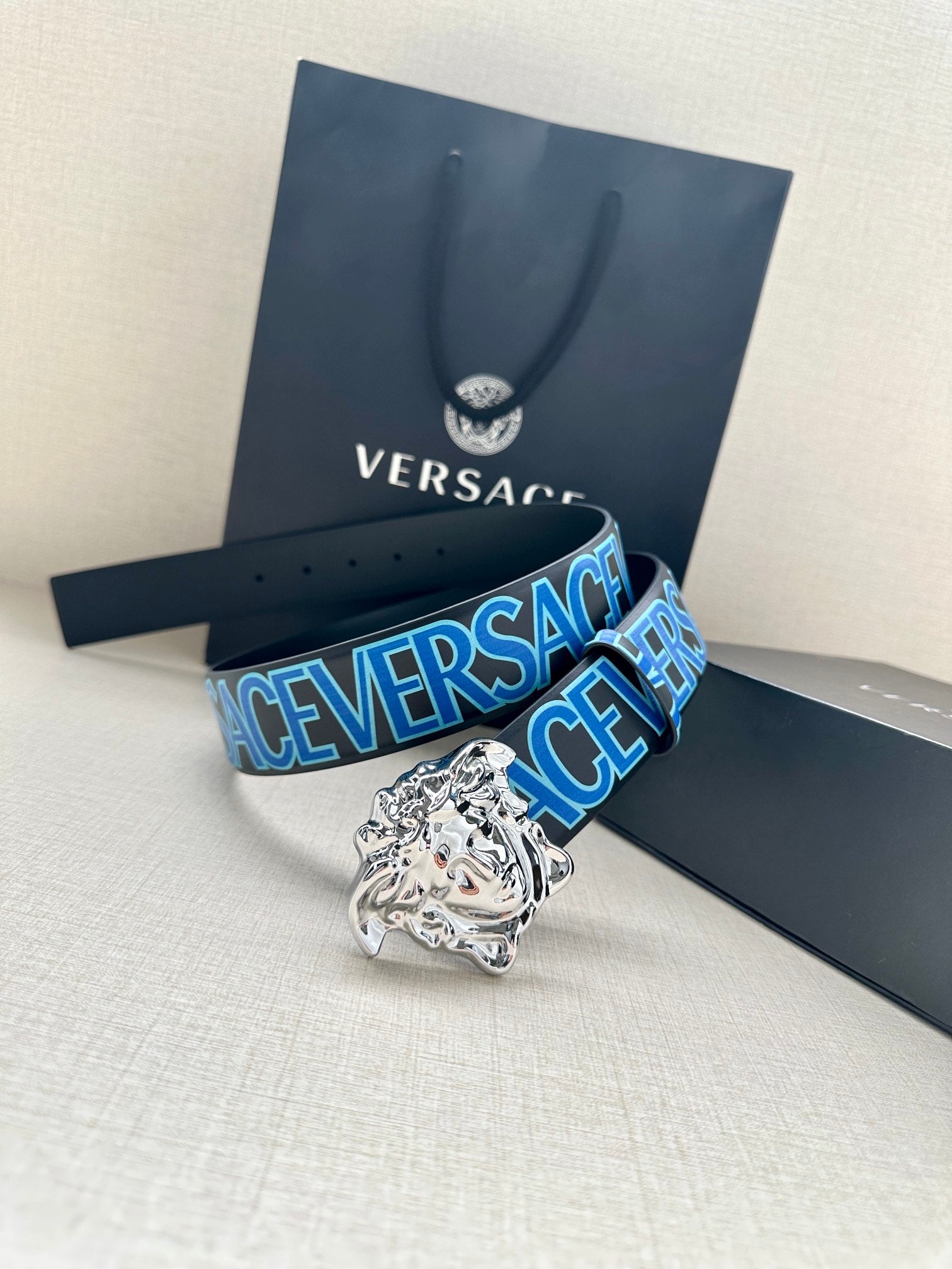 Versace belt with dark strap, blue logo print, and silver Medusa buckle