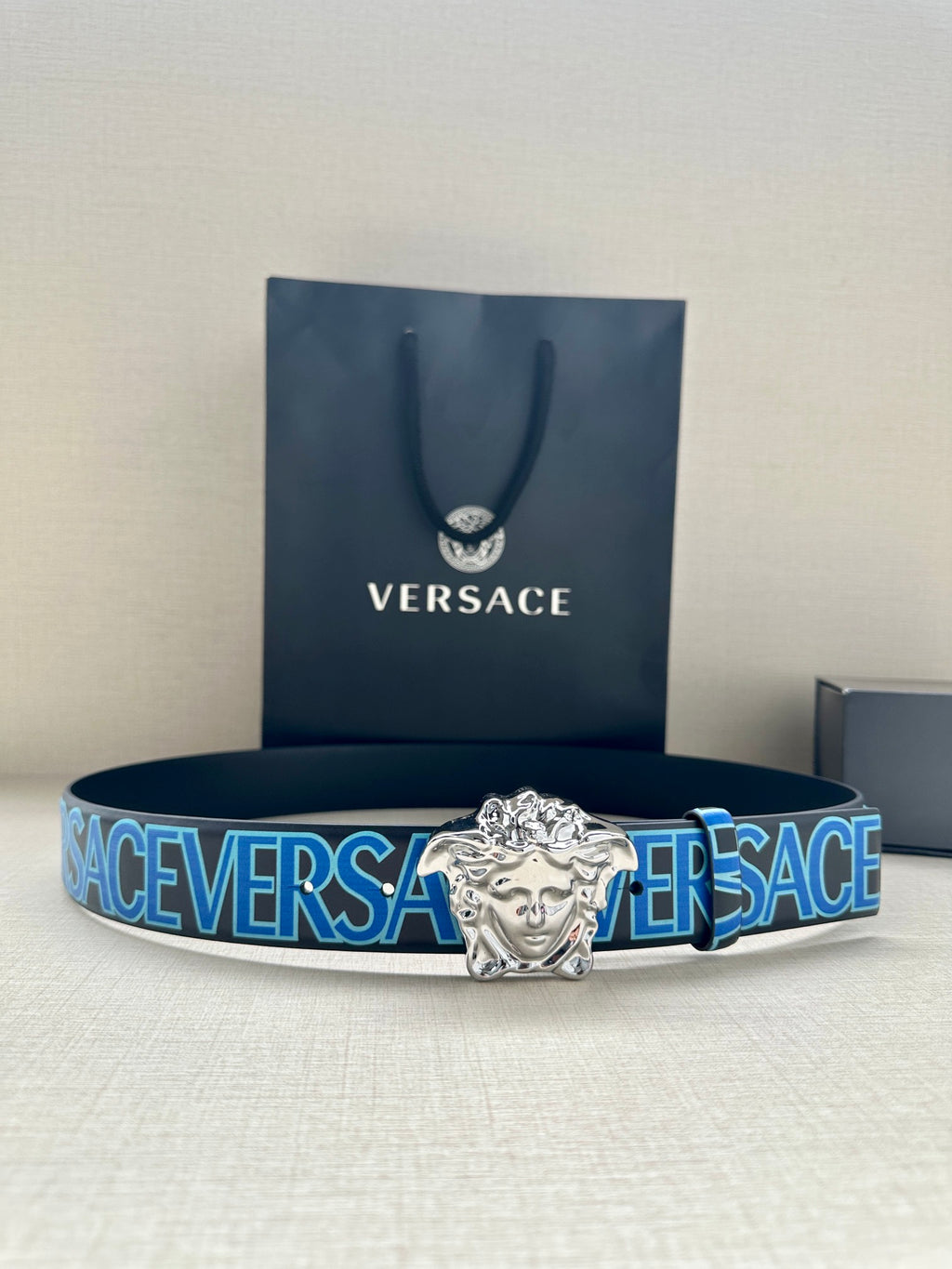 Versace belt with dark strap, blue repeating logo, and silver Medusa buckle