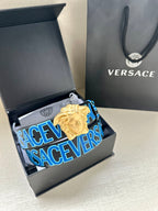 Versace belt in open box: dark blue strap with Versace logo print and gold Medusa buckle.