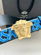 Versace belt buckle close-up: gold Medusa on dark blue strap with blue logo print.
