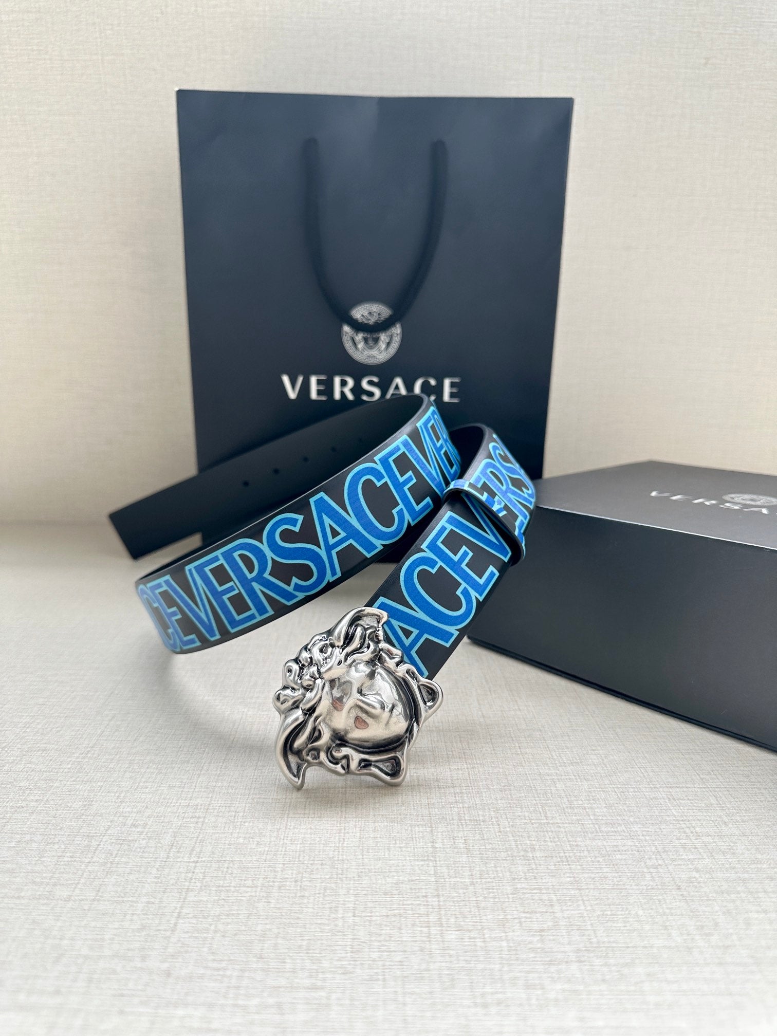 Versace belt: blue logo strap with silver Medusa buckle, angled view