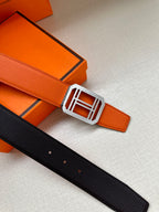 Hermes belt with orange strap and silver buckle, black keeper detail.
